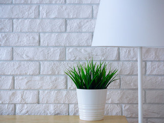 white brick wall with lamp and potted green plant