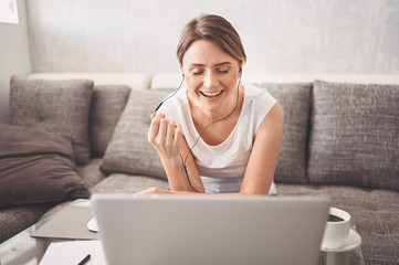 Fototapeta premium Attractive happy young student studying online at home, using laptop computer, headphones, having video chat, waving. Remote work, distance education. Video conference or virtual event on quarantine
