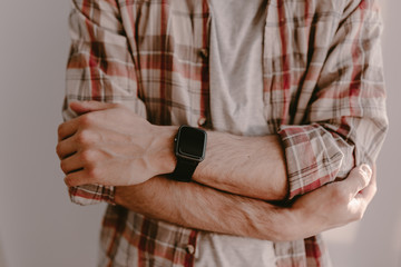 Hipster young man uses his smart watch. Checking the message or calls. Man in plaid shirt. Modern life. Black smart watches. Millennial. Hipster using all modern technologies. Era of modern gadgets.