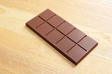 Milk chocolate bar on wooden table.