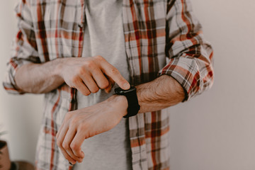 Hipster young man uses his smart watch. Checking the message or calls. Man in plaid shirt. Modern life. Black smart watches. Millennial. Hipster using all modern technologies. Era of modern gadgets.