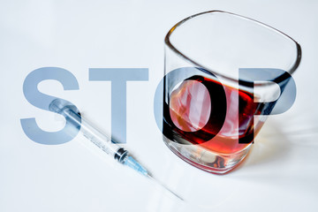 The word stop on the background of a glass with whiskey and a syringe.