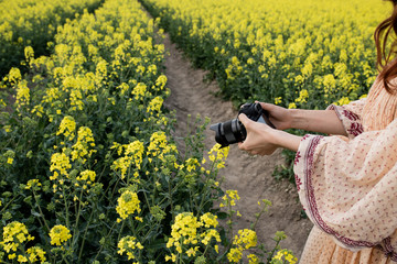 camera in hands on a background of yellow flowers