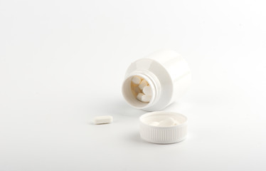 White pills and plastic bottle on a white background.
