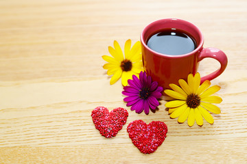 Cup of coffee, flowers and red chocolate hearts.