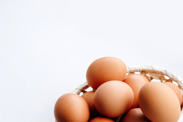 Brown chicken eggs in a straw basket on white wooden background. Top view with copy space.