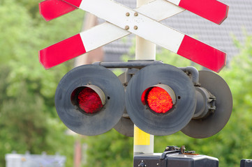 Red stop signal at a level crossing with trees in the background