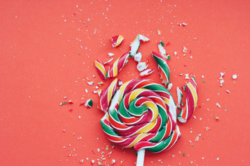 Broken in pieces candy on a stick. Smashed lollipop on orange background.