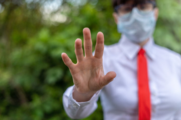 Business woman in mask shows stop hand gesture or reaching for screen. Virus Epidemic Concept.