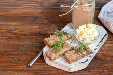 Fresh homemade chicken liver pate with carrots, onions and butter. Garnished with a sprig of dill. Lubricated on bread. On a wooden background.