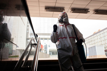 disinfection of the city from viruses and infections. sanitary worker in a protective suit and a respirator cleans the city with a chemical agent