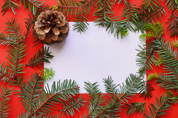 Fototapeta na wymiar Christmas composition on red background. Paper blank, christmas tree branches, Copy space for text. Flatlay for designers. Top view, Greeting Card mock up.