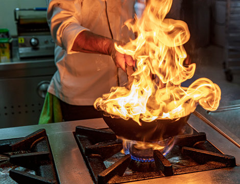 Flambe Chef Cooking in Kitchen. Professional chef in a commercial kitchen cooking flambe style. Chef Flambe Cooking.
