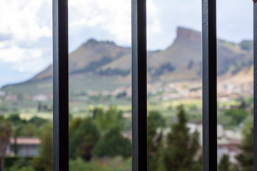 Pandemic Confinement: Mountain Landscape Views Through the Bars of a Home Window