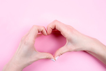 Obraz premium Female hands in the form of heart on pink background. Concept Valentines day, Mothers day. Beautiful hands of woman with copy space.