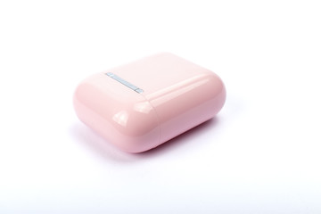 Pink wireless headphones in a case on white background. The concept of technology and progress.