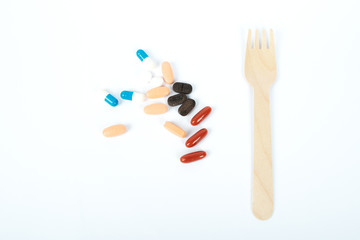 Handful of pills and an eco-friendly disposable fork. Food for illness. Medicine concept. Epidemic coronavirus 2019-nCoV. Flat lay.
