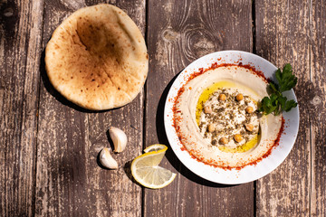 hummus bowls on the white plate with olives oil. Chickpea hummus, lentils hummus on wooden table with pita garlic and lemon