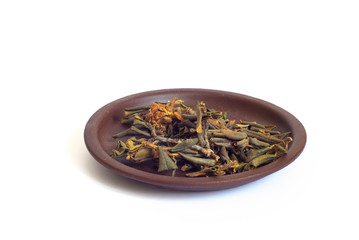 A pile of dried rhododendron Adamsia in a clay plate, Sagan daily for tea. Isolated on a white background close up