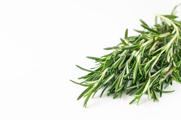Fresh bouquet of rosemary leaves in a white ceramic bowl on white light background. Selective focus.