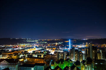Germany, Magical starry night sky over modern buildings of swabian city esslingen am neckar, aerial view above the illuminated houses and roofs by night