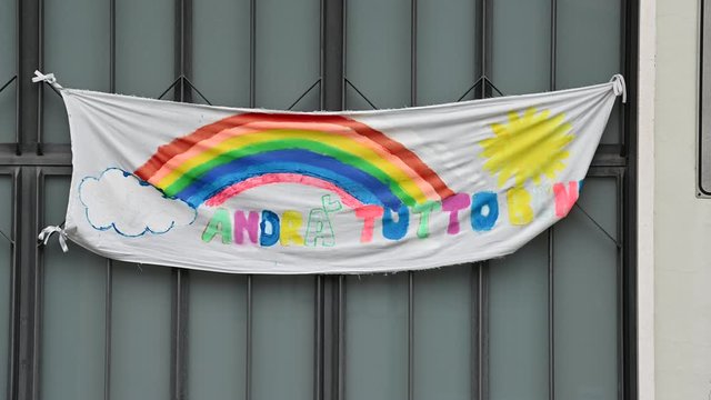 Turin, Piedmont, Italy. May 2020. Coronavirus pandemic. On the facades of the houses hang the sheets with the drawing of the rainbow and message everything will be fine. In Italian "Andr&agrave; tutto bene"