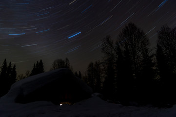 Winter starry sky above the house in the taiga