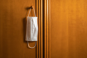 Mascarilla colgada del pomo de un mueble de madera