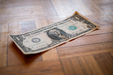 Billete de un dólar americano sobre suelo de madera.