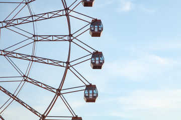 Modern ferris wheel with glazed booths on a background of blue sky without people. The traditional attraction in the park is a symbol of childhood and summer.