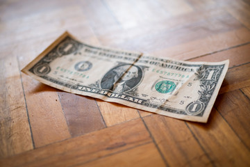 Billete de un dólar americano sobre suelo de madera.