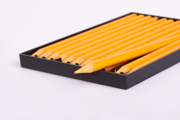New yellow wooden pencils in black plastic box tin isolated on white background