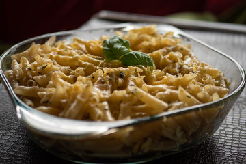 Macarrones al pesto en recipiente de cristal.