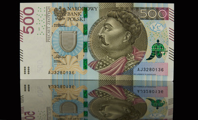Pojedynczy banknot leżący na czarnym tle i jego odbicie lustrzane