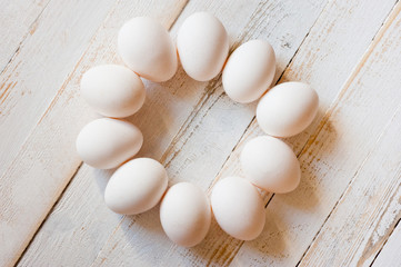 White chicken eggs lying on a white painted wooden surface. Background for livestock products.