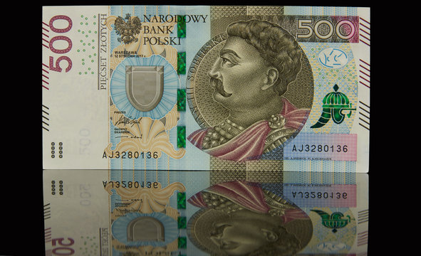 Pojedynczy banknot leżący na czarnym tle i jego odbicie lustrzane