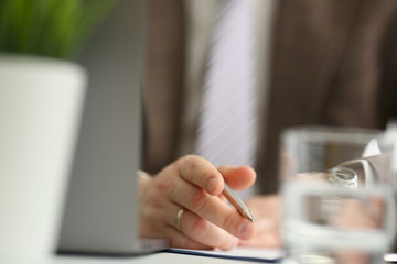 Male arm in suit and tie hold silver pen filling schedule
