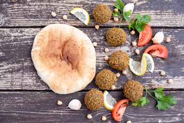 falafel balls from hummus on the wooden table with design lemon and parsley on wooden background with cilantro Vegetarian dish -  from spiced chickpeas food flat lay