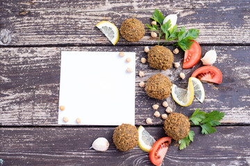 falafel balls from hummus on the wooden table with design lemon and parsley on wooden background with cilantro Vegetarian dish -  from spiced chickpeas food flat lay