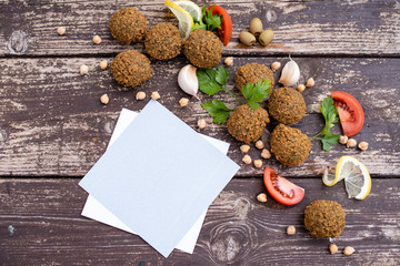 falafel balls from hummus on the wooden table with design lemon and parsley on wooden background with cilantro Vegetarian dish -  from spiced chickpeas food flat lay