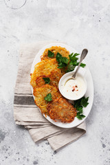 Draniki - potatof ritters, vegetarian potato pancakes, served with fresh herbs and garlic yogurt sauce, top view.