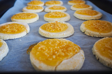 round gluten-free cookies made from rice flour and cottage cheese with orange jam and crushed almonds on parchment paper. gluten-free diet. homemade baking cookies. nut sprinkles