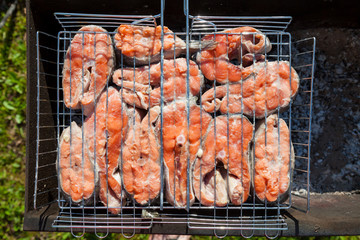 Closeup of steaks of red appetizing fish rich in saturated fatty acids, vitamins, iodine and phosphorus - coho salmon on the grill is grilled on charcoal in the barbecue.