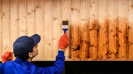 Back view of young man contractor worker paint with brush