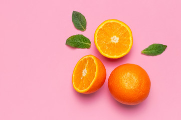 Fruit, creative summer concept. Fresh juicy whole and sliced orange, mint leaves on pink background. Flat lay Top view copy space. Minimalistic background with citrus fruits, vitamin C. Pop art design