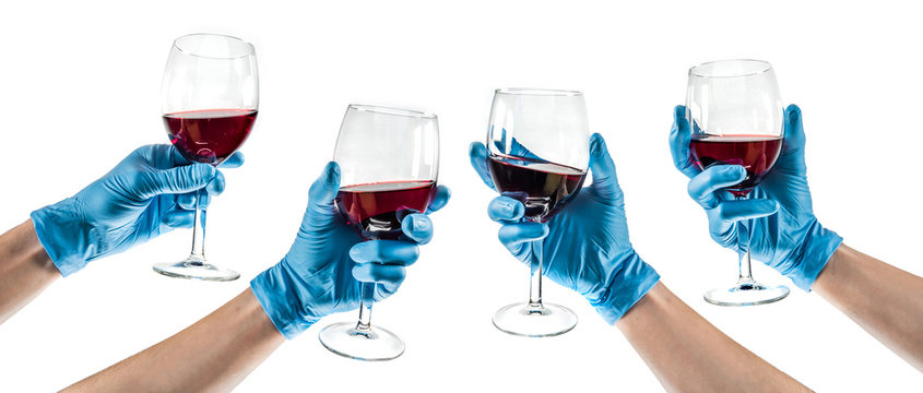 Varias manos con guantes de l&aacute;tex sujetando una copa de vino tinto.