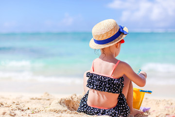 Little girl at tropical white beach making sand castle