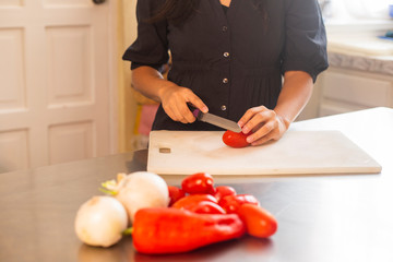 detail of woman hands cutting vegetables in her kitchen - young woman cooking vegan food - salad, healthy food