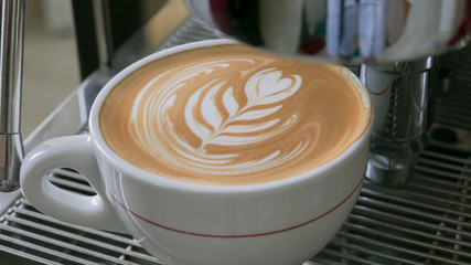 detail of prepared cappuccino with latte art on a coffee machine, coffemaker (color toned image)