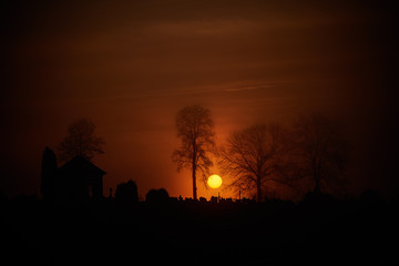 Krwawy wschód słońca nad starym cmentarzem